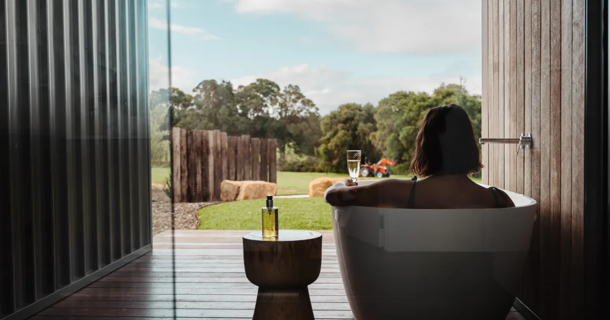 Woman sitting in an outdoor bath looking out toward the trees.