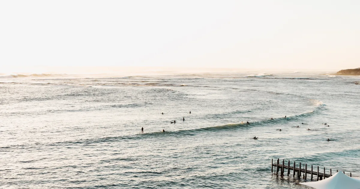 Gnarabup Beach with the jetty and surfers in the water. Swell Stays holiday accommodation image in Margaret River
